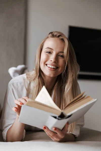 Mujer Joven Sonriente Sosteniendo Libro Abierto Blanco Mientras Relaja Sofá — Foto de Stock