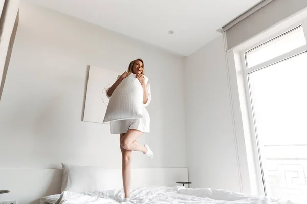 Genç Mutlu Güzel Kadın Kapalı Evde Yatakta Yastık Ile Atlama — Stok fotoğraf