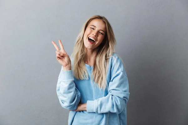 Portrait Lovely Young Girl Blue Sweatshirt Showing Peace Gesture Isolated — Stock Photo, Image
