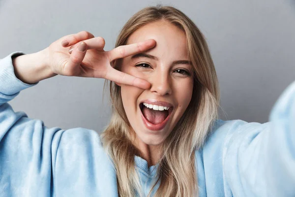 Zbliżenie Uśmiechający Się Młoda Blondynka Biorąc Selfie Pokazuje Gest Pokoju — Zdjęcie stockowe