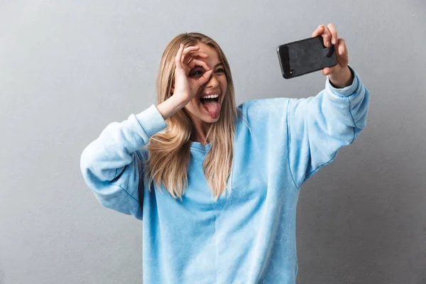 Smiling Young Blonde Girl Taking Selfie Showing Gesture Isolated Gray — Stock Photo, Image