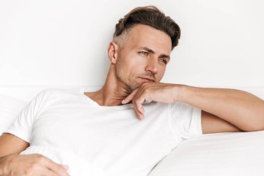 Yatakta döşeme ve uzağa bakarak konsantre adam