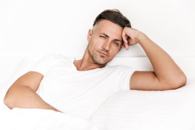 Yatakta döşeme ve kameraya bakarak rahat adam