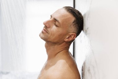 Duş yaparken bir duvara yaslanmış bir yakışıklı adamın yakın çekim