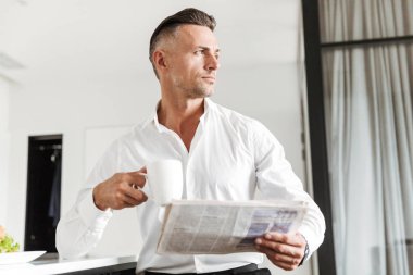 Yakışıklı bir mutfak ile bir gazete üzerinde otururken kahvaltı resmi elbise giymiş