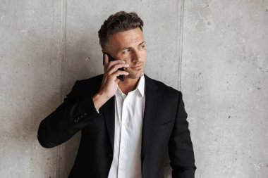 Cep telefonu gri duvar arka plan üzerinde uymak yakışıklı adam giymiş