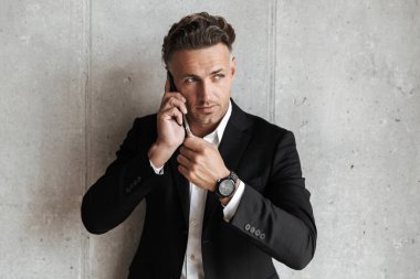 Uymak cep telefonu gri duvar arka plan üzerinde kendine güvenen adam giymiş