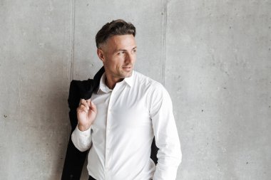 Uzak gri duvar arka plan üzerinde seyir omzunun üzerinden erkek ceket ile gülümseyen