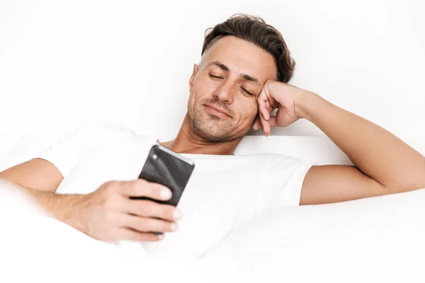 Uśmiechnięty Mężczyzna Pomocą Telefonu Komórkowego Relaksując Się Łóżku — Zdjęcie stockowe