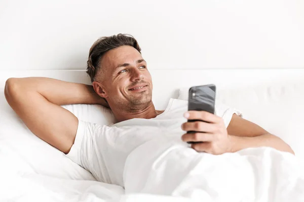 Усміхнений Чоловік Тримає Мобільний Телефон Ліжку — стокове фото