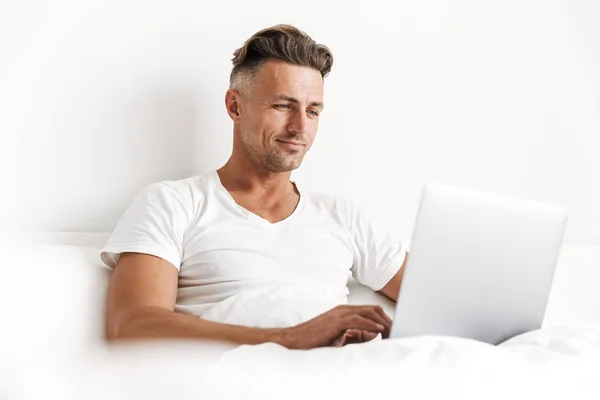 Uomo Sorridente Che Utilizza Computer Portatile Mentre Seduto Letto — Foto Stock