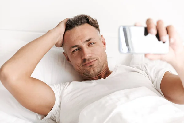 침대에 전화와 Selfie를 매력적인 남자의 클로즈업 — 스톡 사진