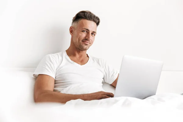 Hombre Feliz Usando Ordenador Portátil Mientras Está Sentado Cama —  Fotos de Stock