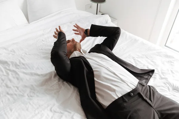 Desperate Man Dressed Suit Lying Bed Arms His Face — Stock Photo, Image