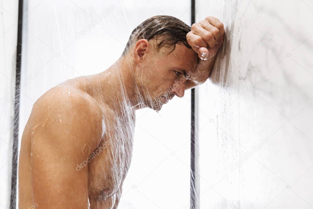 Confident muscular man taking a shower