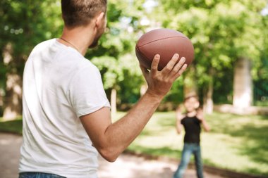 Genç baba resmi var açık havada park doğada küçük oğlu ile topu oyun eğlenceli.