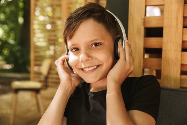 Neşeli çocuk kulaklık ile müzik dinleme Cafe Doğa oturan imajının.