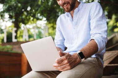 Genç adam açık havada dizüstü bilgisayar kullanan görüntü kırpılmış.