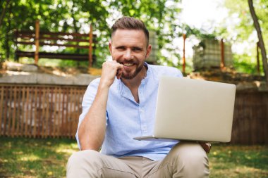 Genç adam açık havada kamera seyir dizüstü bilgisayar kullanan fotoğrafı.