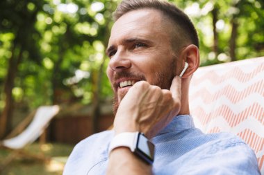 Mutlu genç sakallı adam açık havada dinleme müzik kulaklık ile fotoğraf.