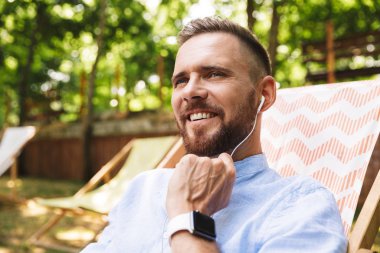 Mutlu genç sakallı adam açık havada dinleme müzik kulaklık ile fotoğraf.