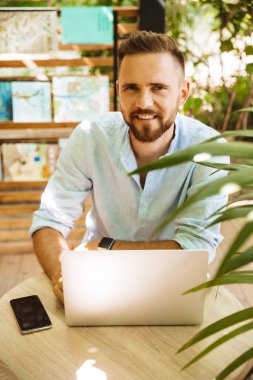 Fotoğraf gülümseyen duygusal Genç sakallı adam açık havada dizüstü bilgisayar kullanan.