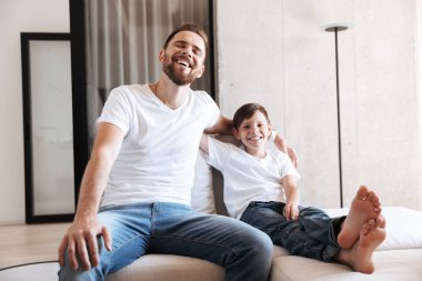 Neşeli genç adam baba baba ile oğlu kapalı Ev Tv izlerken eğlenmek görüntüsünü.