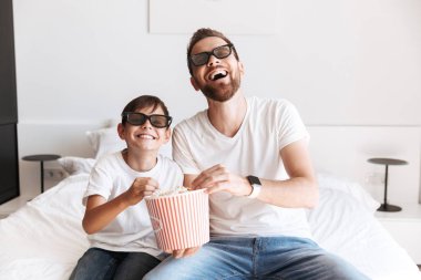 Neşeli genç adam baba baba ile oğlu kapalı evde 3d gözlük takan pop mısır yemek Tv izlerken eğlenmek fotoğrafı.