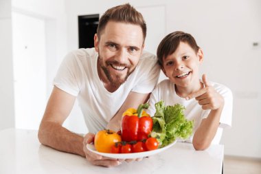 Neşeli genç adam baba baba oğluyla evde kapalı mutfak pişirme fotoğraf. Görünümlü kamera.