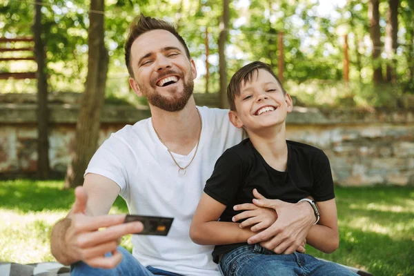 Photo Happy Young Father Sitting His Little Son Outdoors Park — Stock Photo, Image