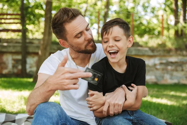 Photo Happy Young Father Sitting His Little Son Outdoors Park — Stock Photo, Image