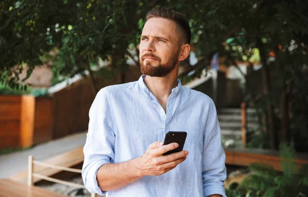 Yakışıklı genç sakallı adam açık havada bir kenara istimal hareket eden telefon görünümlü görüntü.