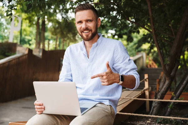 Mutlu duygusal Genç sakallı adam açık havada bilgisayar dizüstü işaret kullanarak görüntü.