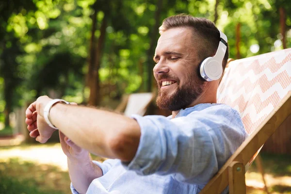 Mutlu heyecanlı duygusal Genç sakallı adamın eli açık havada dinleme müzik kulaklık ile nöbet ile fotoğraf.