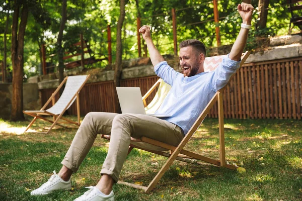 Duygusal Genç sakallı adam açık havada dizüstü bilgisayar kullanan fotoğraf olun kazanan jest.