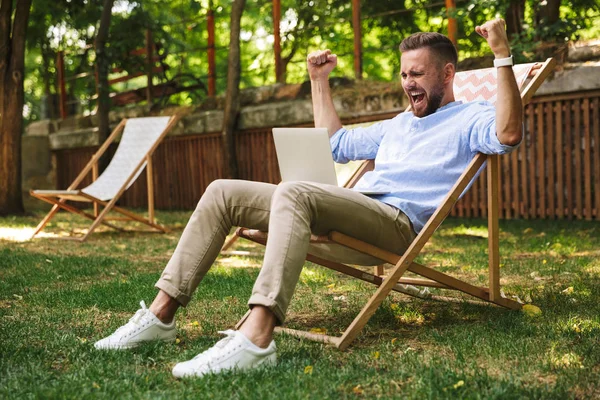 Duygusal Genç sakallı adam açık havada dizüstü bilgisayar kullanan fotoğraf olun kazanan jest.