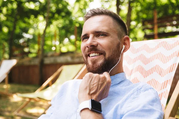 Mutlu genç sakallı adam açık havada dinleme müzik kulaklık ile fotoğraf.
