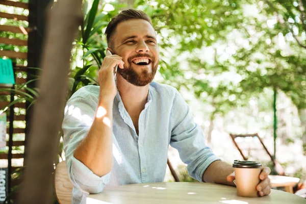 Фото Красивого Счастливого Молодого Бородатого Человека Смотрящего Сторону Разговаривающего Мобильному — стоковое фото