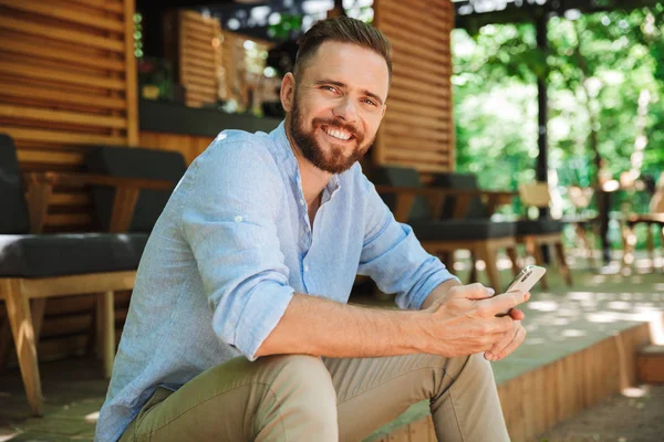 Fotoğraf gülümseyen duygusal Genç sakallı adam açık havada istimal hareket eden telefon fotoğraf makinesi arıyorum.