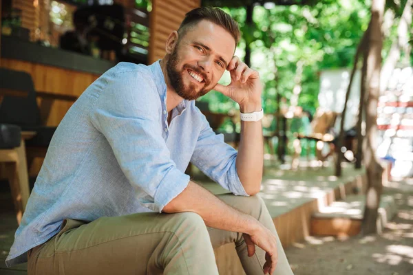 Açık havada görünümlü kamera oturan genç sakallı adam fotoğrafı.