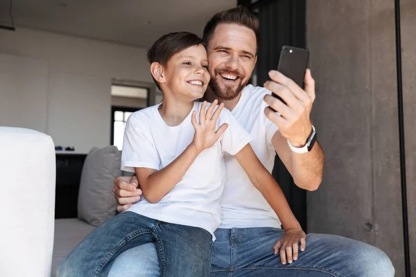 Yakışıklı sakallı adam kapalı evde cep telefonu sallayarak kullanarak onun oğlu çocuk ile görüntü.