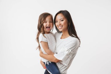 Beyaz duvar arka plan üzerinde izole küçük kız çocuk kızı annesiyle mutlu Genç Asyalı kadın görüntüsünü.
