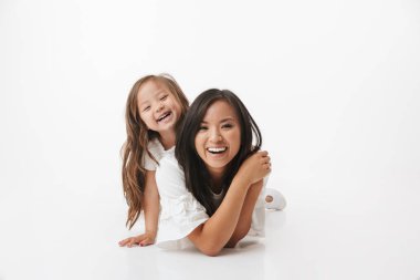Sevimli Genç Asyalı kadın anne küçük kız çocuk kızıyla birlikte görüntüsünü beyaz duvar arka plan üzerinde izole katta yatıyor.