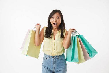 Mutlu duygusal Genç Asyalı kadın üzerinde beyaz duvar arka plan alışveriş torbaları ile izole görüntüsünü.