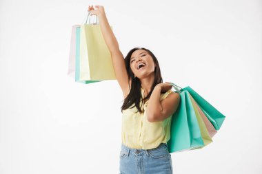 Mutlu duygusal Genç Asyalı kadın üzerinde beyaz duvar arka plan alışveriş torbaları ile izole görüntüsünü.