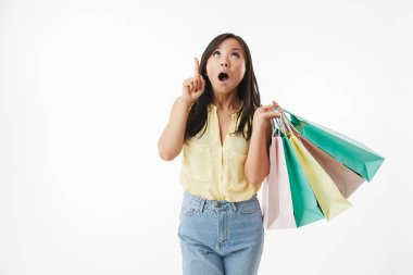 Şok duygusal Genç Asyalı kadın beyaz duvar arka plan üzerinde alışveriş torbaları ile işaret izole görüntüsünü.