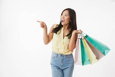 Mutlu duygusal Genç Asyalı kadın beyaz duvar arka plan üzerinde alışveriş torbaları ile işaret izole görüntüsünü.