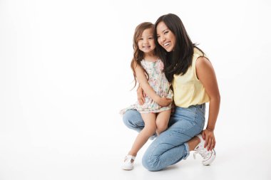 Beyaz duvar arka plan üzerinde izole küçük kız çocuk kızı annesiyle mutlu Genç Asyalı kadın görüntüsünü.