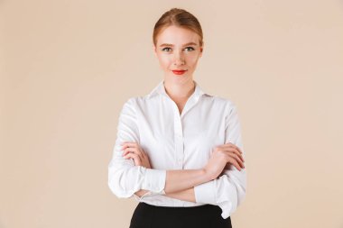 Görüntü izole kamera seyir bej duvar artalan üzerinde duran muhteşem genç iş kadını.