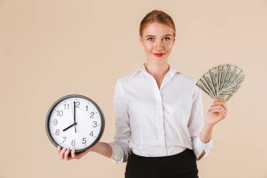 Bej renkli arka plan üzerinde izole para banknot ve duvar saati gösteren gülümseyen bir iş kadını portresi